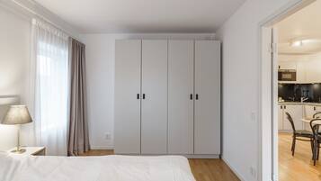 A bedroom with a bed, a nightstand, a lamp, and a wardrobe.