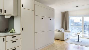 A modern living room with a sofa, a dining table, and a kitchen area with cabinets and a countertop.