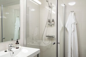 Un baño moderno con cabina de ducha de vidrio, lavabo blanco y espejo.