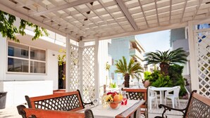 An outdoor patio with wooden benches, a table with fruit and a glass, and a white fence. - Sunny Escape near Silver Beach for 3 (Alba Adriatica (TE))