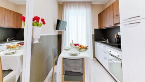 Een moderne keuken met witte kasten, een eettafel gedekt voor twee personen en een tv aan de muur.