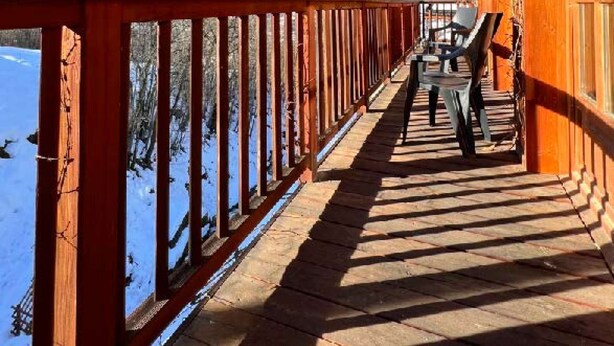 Un balcón de madera con vistas a montañas nevadas.