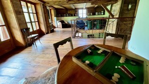 Una habitación acogedora con vigas de madera, una mesa de billar y una ventana con vistas.