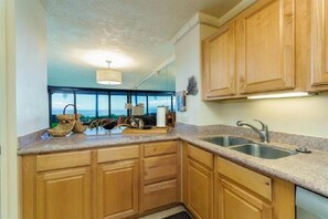 Kitchen features a double sink, modern faucet, and a window with an outdoor view.