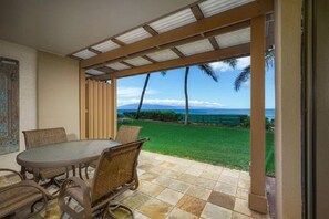 Enjoy a serene meal with a view of the lawn and distant shoreline from this covered outdoor dining area.