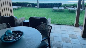 En patio med udendørs møbler, et bord med en skål, og udsigt til havet.