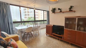 Una sala de estar con televisor, aparador de madera, mesa de comedor, sillas y sofá.