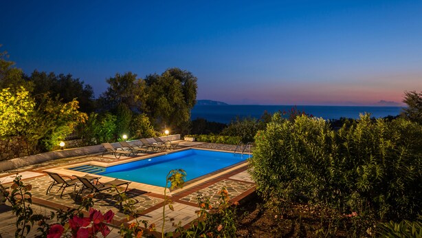 A rectangular swimming pool with a stone border, surrounded by lounge chairs and a stone wall. - Villa Rudi (Argostoli)