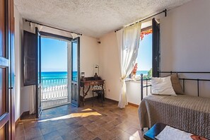 Enjoy a sea view from the balcony, featuring a comfortable bed, desk, and window with curtains.