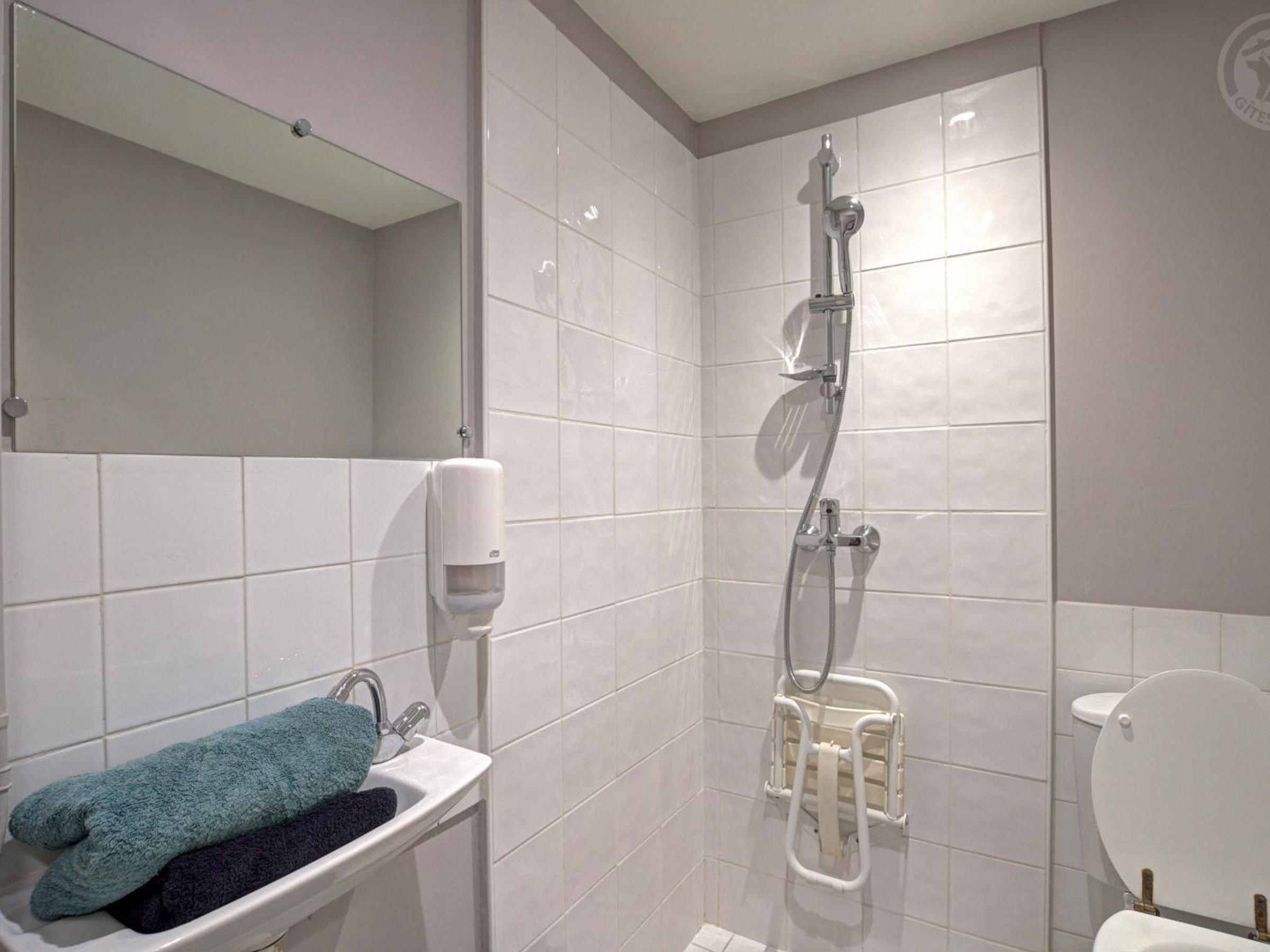 A bathroom with a sink, a towel rack, a toilet, and a shower.