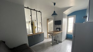 A modern kitchen with a dining area, a built-in wardrobe, and a TV mounted on the wall.