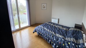 A bedroom with a large window, a bed, a radiator, and a picture on the wall. - Central Apartment with Balcony, Wi-Fi & Dishwasher - Near Shops & Spa (La Roche-Posay)