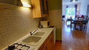 A kitchen with two sinks, a stove, and wooden cabinets. - Central Apartment with Balcony, Wi-Fi & Dishwasher - Near Shops & Spa (La Roche-Posay)