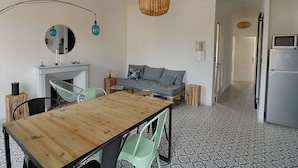 A modern living room with a wooden dining table, a sofa, and a fireplace. - Ajaccio: Charming 2BR, 4 guests, Wifi, Downtown (Ajaccio)