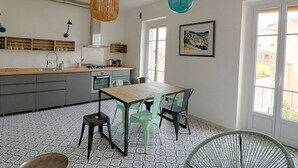 A modern kitchen with a wooden countertop, grey cabinets, and a dining area with a wooden table and green chairs. - Ajaccio: Charming 2BR, 4 guests, Wifi, Downtown (Ajaccio)
