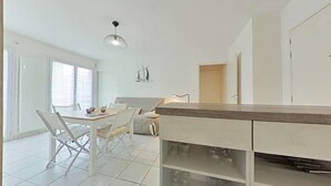 Eine moderne Küche mit weißen Schränken, einem Essbereich mit Tisch und Stühlen sowie einer Pendelleuchte.