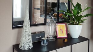 A black console table with a potted plant, a glass jar, a decorative cone, a framed picture, and a small speaker. - House 300 metres from the beach (LOCTUDY)