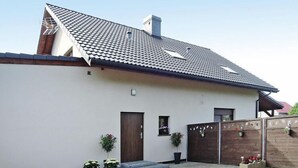 Une maison moderne avec un toit en pente, une porte en bois et une petite fenêtre.