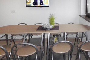 A conference room with a long table, chairs, a small plant, and a television mounted on the wall.