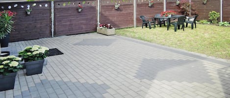 A paved patio area with outdoor furniture and potted plants.