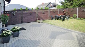 Un espace patio avec un sol en briques, des plantes en pot, une clôture en bois et du mobilier d’extérieur.