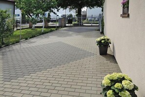 Walkway leads to a secure gated entrance with a potted plant by the side.
