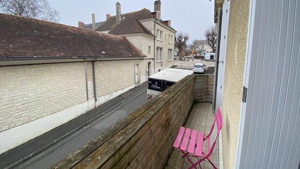 A narrow urban street with residential buildings, a parked car, and a pink folding chair on the sidewalk. - **Cozy T2 in Central La Roche-Posay w/ Wi-Fi, Balcony & Close to Thermes** (La Roche-Posay)