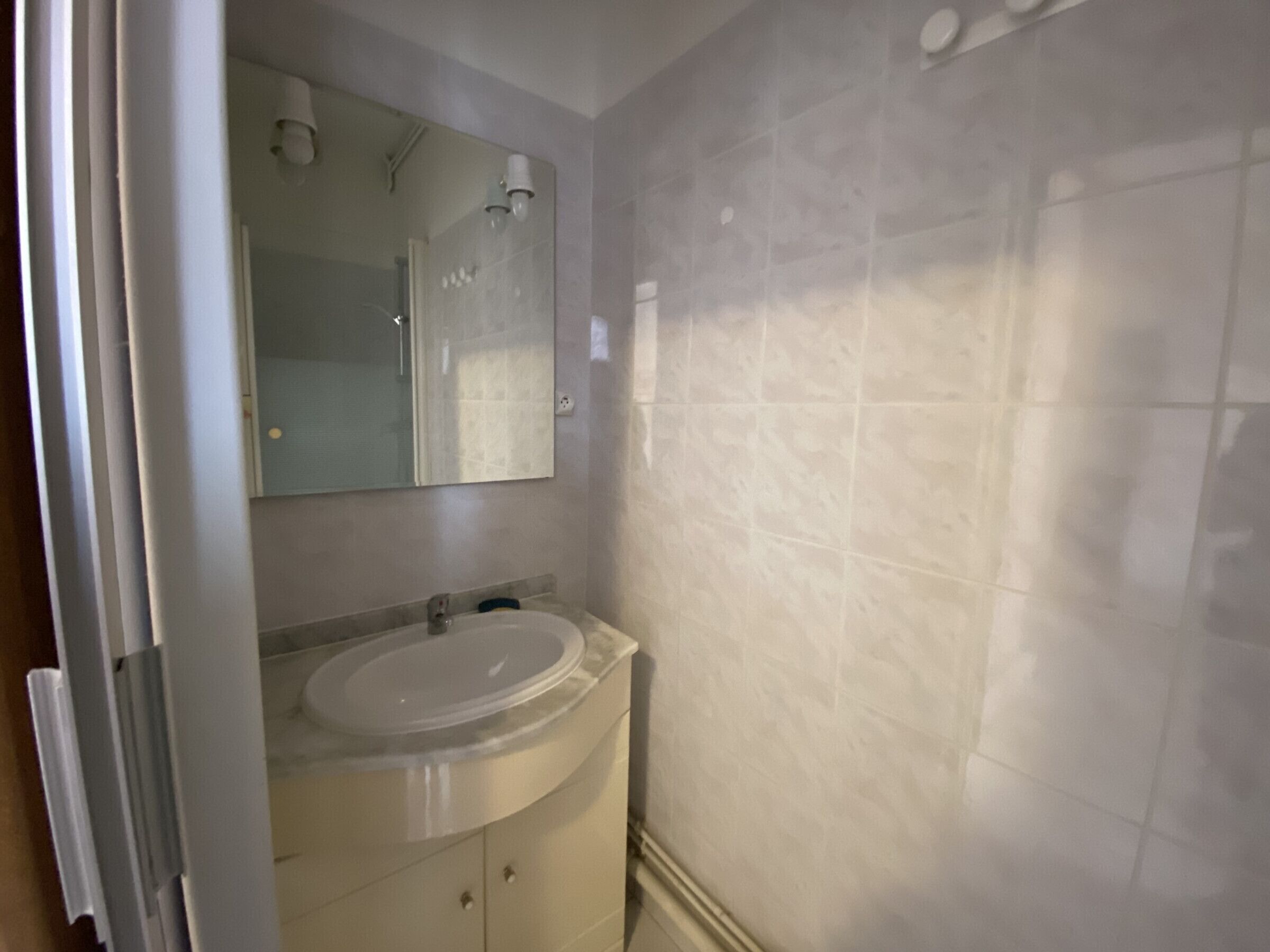 Une salle de bain avec un lavabo, un miroir et des murs carrelés.