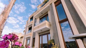 A modern building with multiple balconies, large windows, and a clear sky.