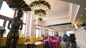 A spacious lobby with a large chandelier, a statue, and modern seating arrangements.