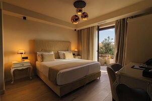 Una habitación de hotel con una cama grande, mesitas de noche, un escritorio y vistas al exterior.
