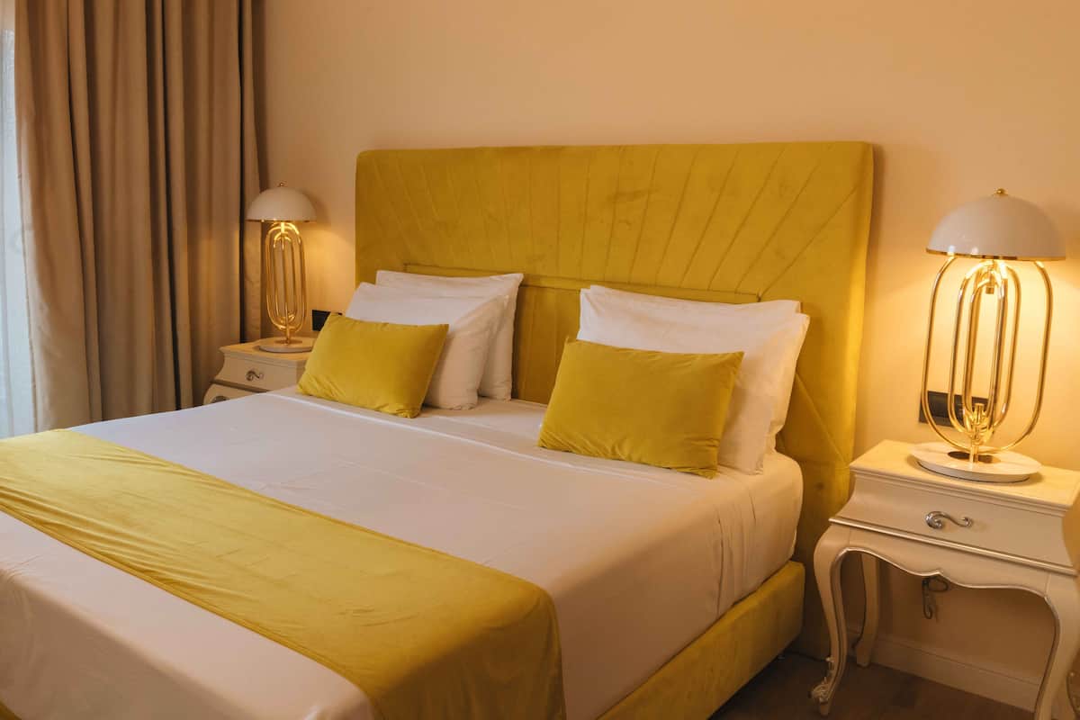 Habitació d'hotel amb un llit gran, dues taules de nit i una petita taula auxiliar amb làmpades.