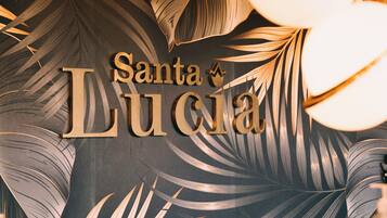 A wall with the text "Santa Lucia" and a palm leaf pattern.