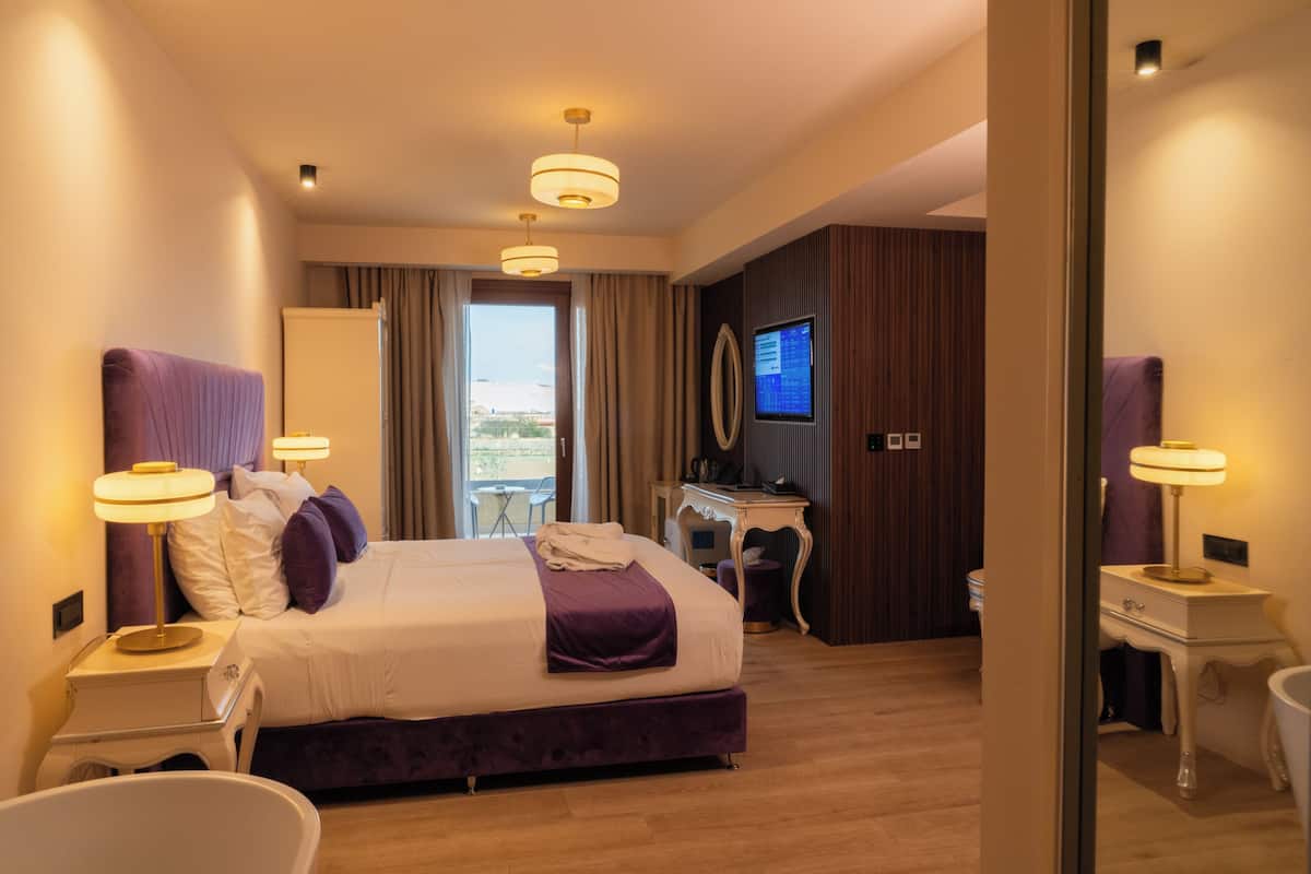 Una habitació d'hotel moderna amb un llit gran, taules de nit, escriptori i televisió.