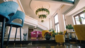 A lobby with a chandelier, plush seating, and potted plants.