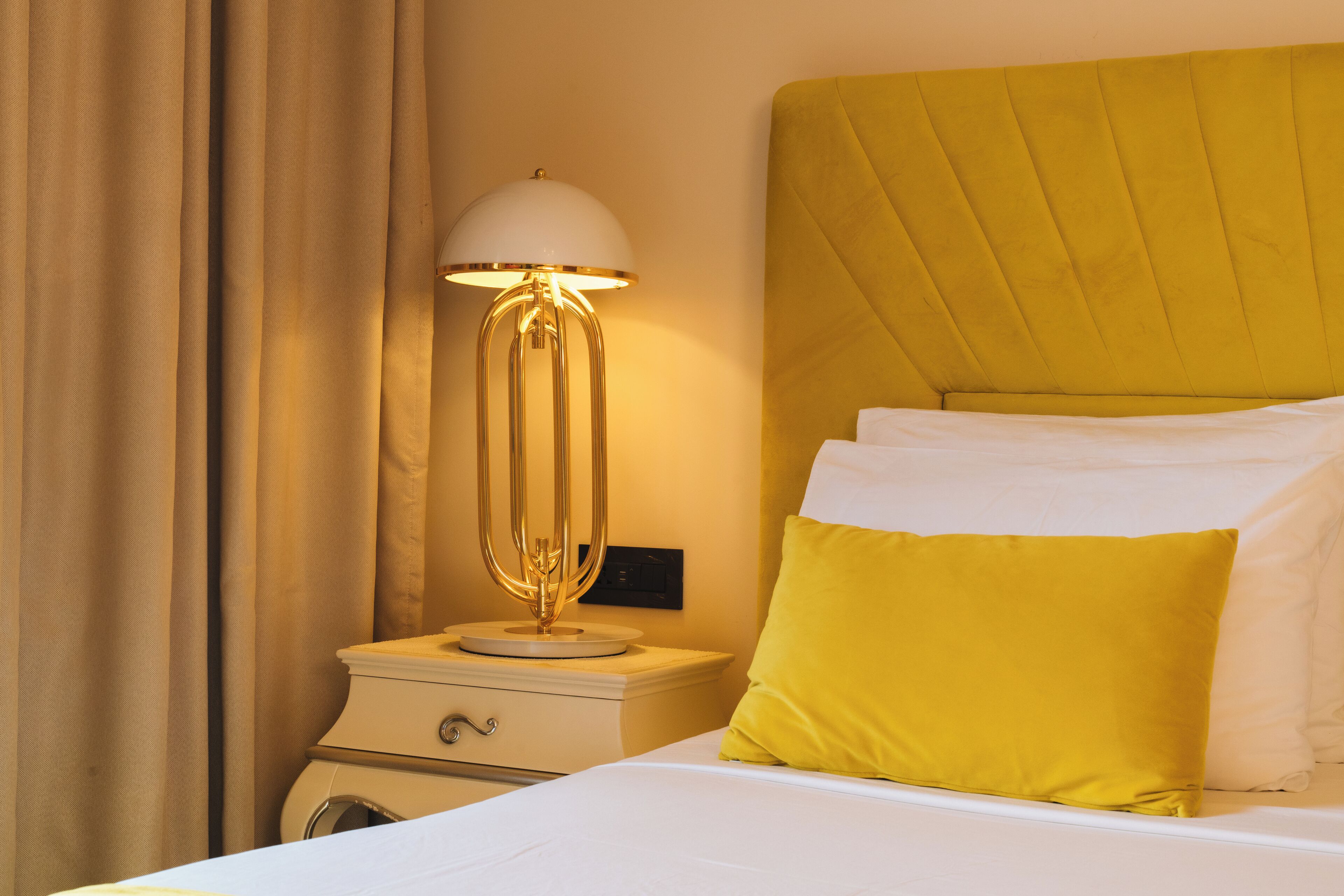 Habitación de hotel con cama, lámpara de noche, mesita de noche y lavadora.