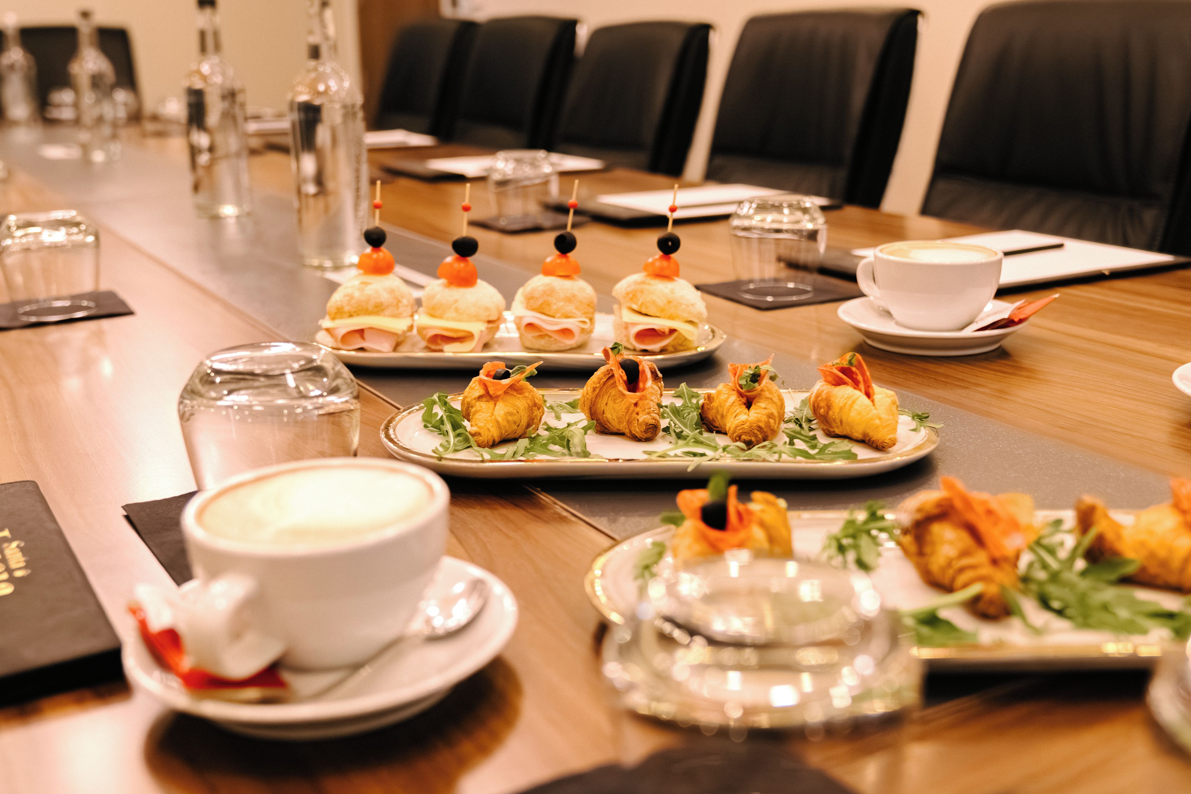 A conference table with food, cups, and glasses.