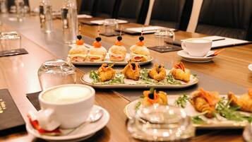 A conference table with food, cups, and glasses.