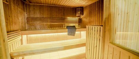 Una sauna con paredes y bancos de madera, suelo de baldosas y un banco con una toalla.