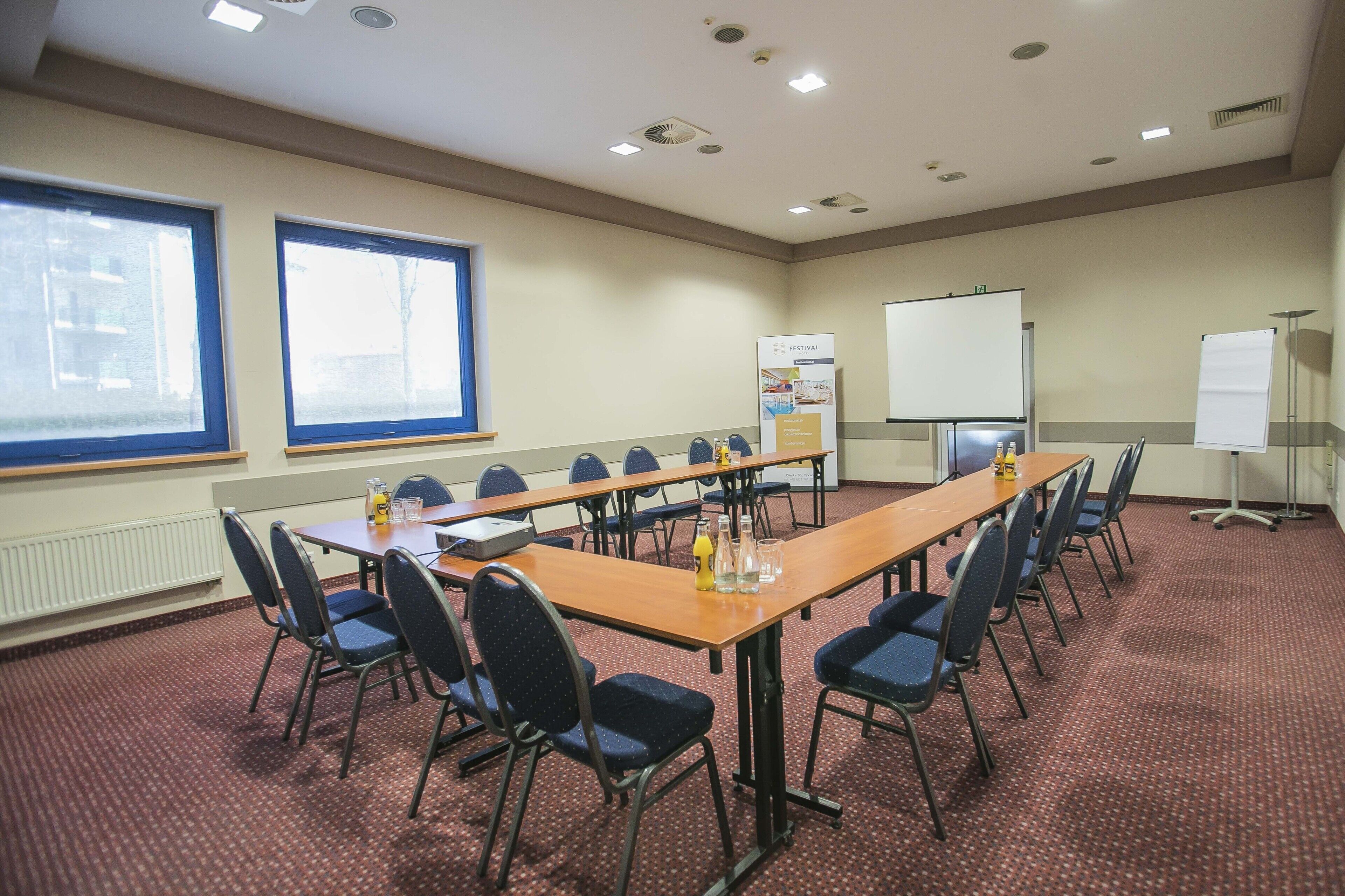 Une salle de conférence équipée d’une longue table, de chaises, d’un tableau blanc et d’un écran de projection.
