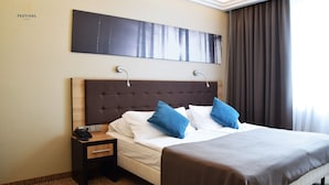 A hotel room with a large bed, a wooden headboard, a nightstand with a phone, and a painting on the wall. - Hotel Festival (Opole)