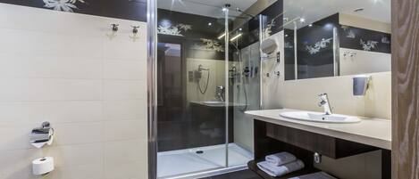 A modern bathroom with a glass-enclosed shower, a vanity with a sink, and a mirror.