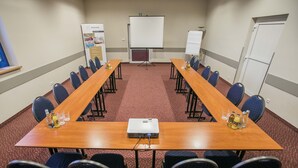 A conference room with a long table, chairs, a projector, and a whiteboard. - Hotel Festival (Opole)