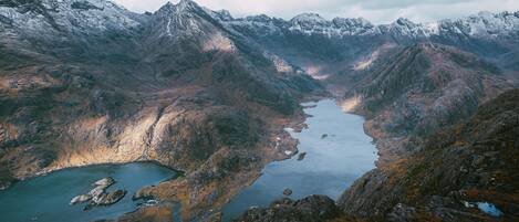 A mountainous landscape with a lake surrounded by rocky terrain and snow-capped peaks.