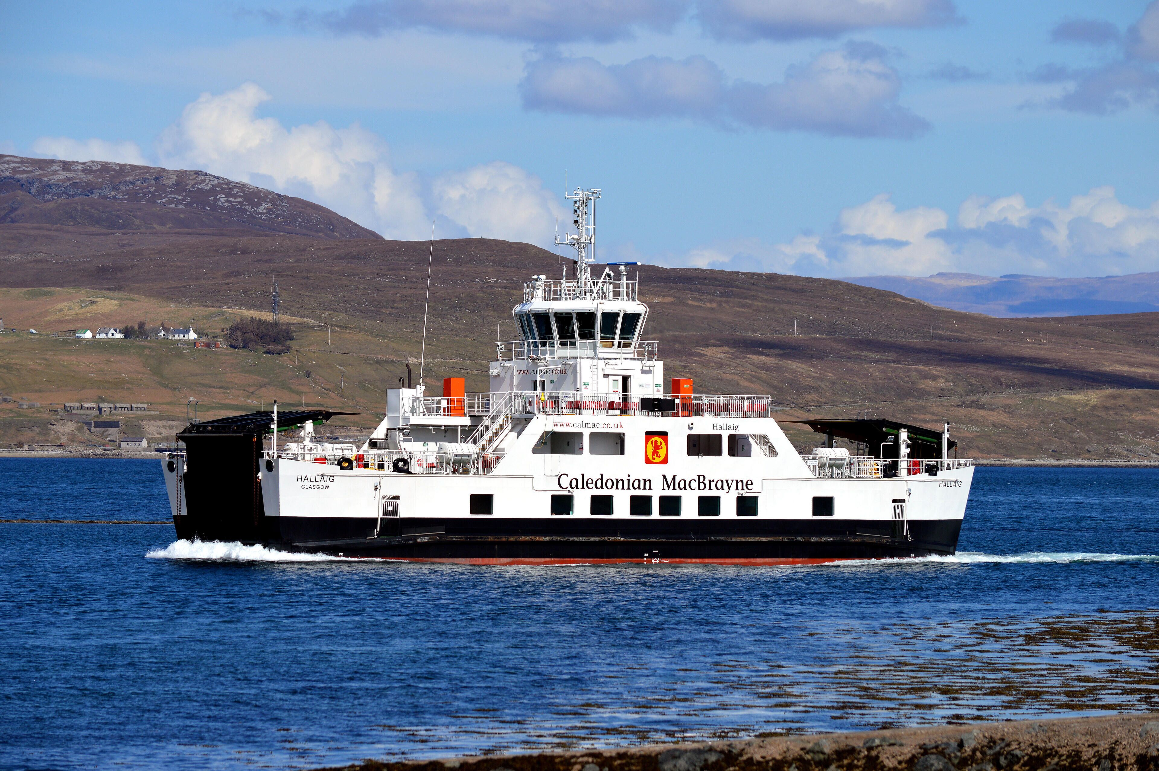 A ferry named Caledonian MacBrayne traveling on a body of water with a mountainous landscape in the background.