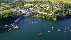 An aerial view of a coastal town with a marina filled with boats, surrounded by residential buildings and greenery. - Kinloch Ainort Apartments  (Sconser)