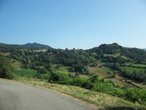 A rural landscape with rolling hills, a road, and scattered buildings.