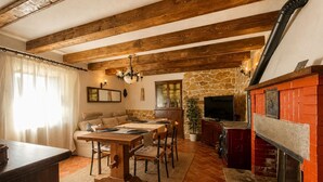 A rustic interior with exposed wooden beams, a stone wall, a fireplace, and a dining area with a table and chairs. - Tuscan House in the Green (Toscana)
