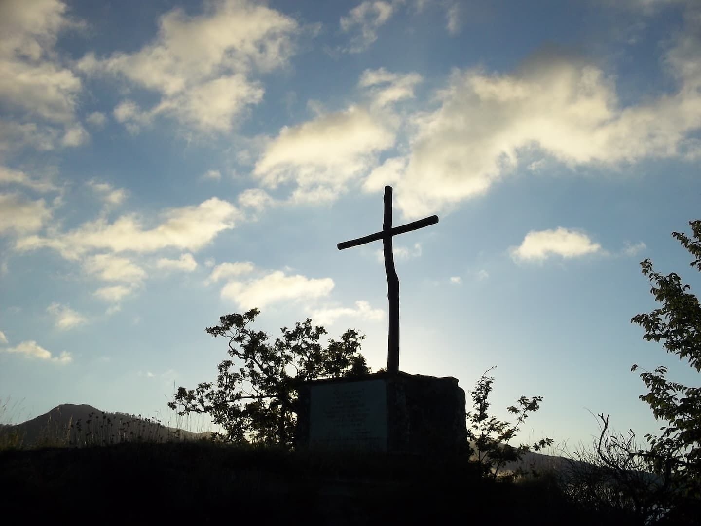 A cross on a stone base with a clear sky in the background.