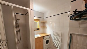 A compact bathroom with a shower, a washing machine, and a radiator. - Cozy 4-person apartment with balcony & garage in Samoëns (Samoëns)